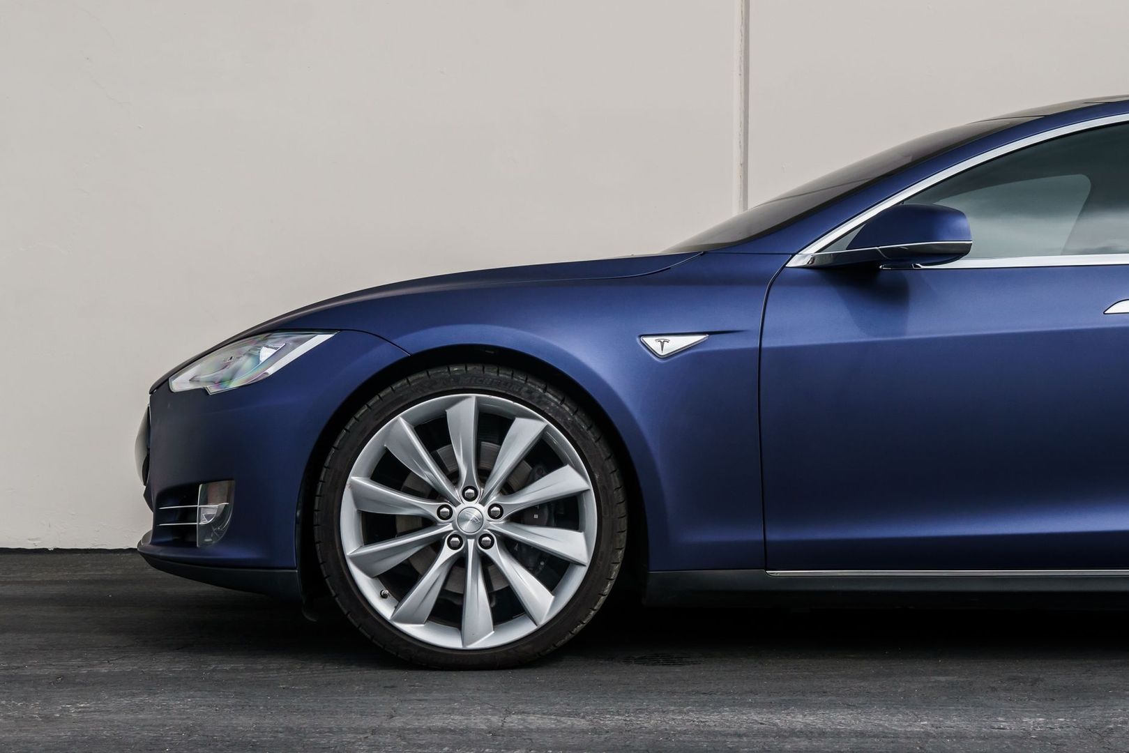 Seitliche Nahaufnahme eines dunkelblauen, stromlinienförmigen Tesla-Elektroautos